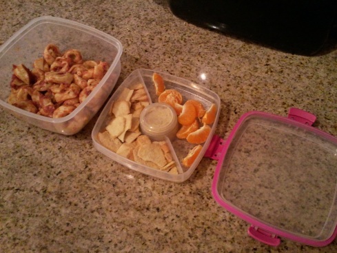 Salad To Go container packed with cheese tortellini in the lower portion, tangerine and pita chips in the upper portion, and hummus in the small round conatiner