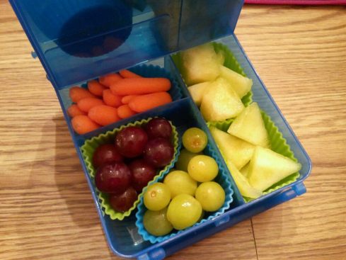 Bottom part of Bright Bin packed with baby carrots, grapes, and honeydew